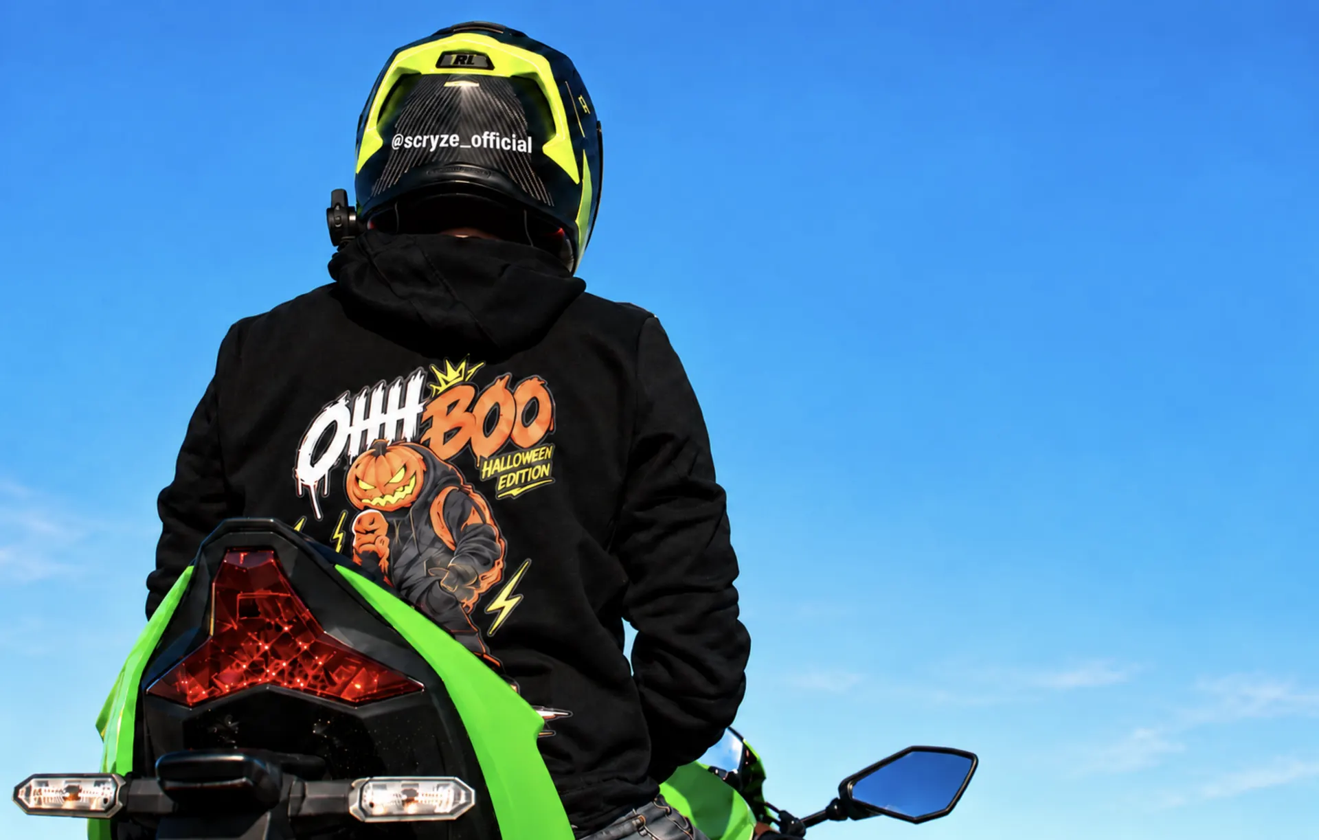SCRYZE mit Helm auf einem grünen Motorrad sitzend